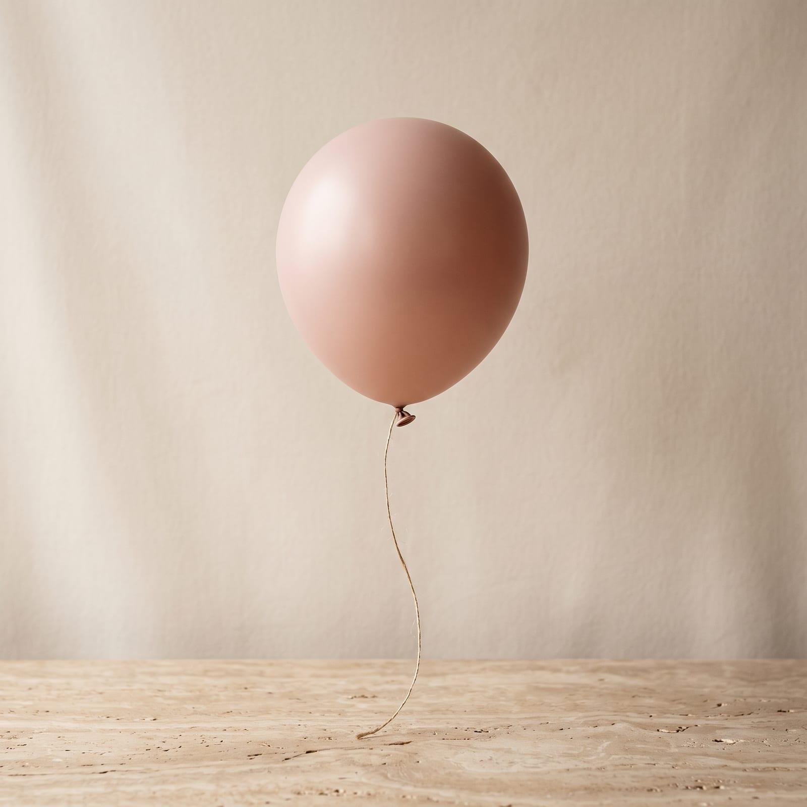 Matter roséfarbener Ballon an einer Schnur